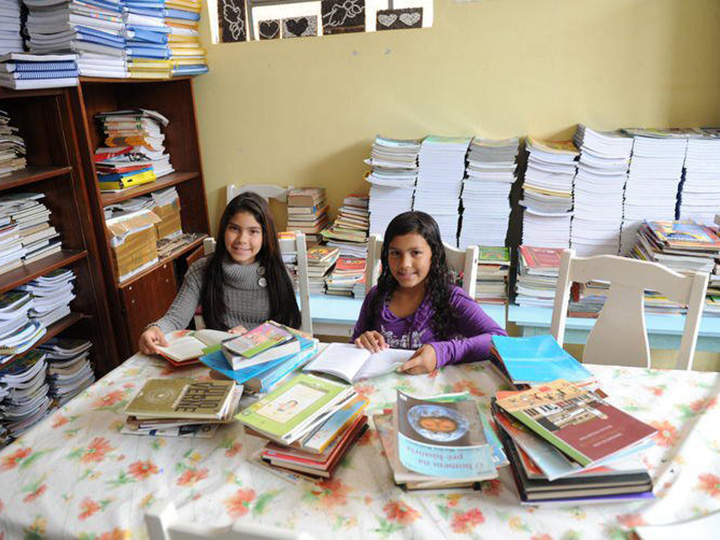 从projeto的照片resgate  - 两个女孩微笑，而在图书馆探索书籍。